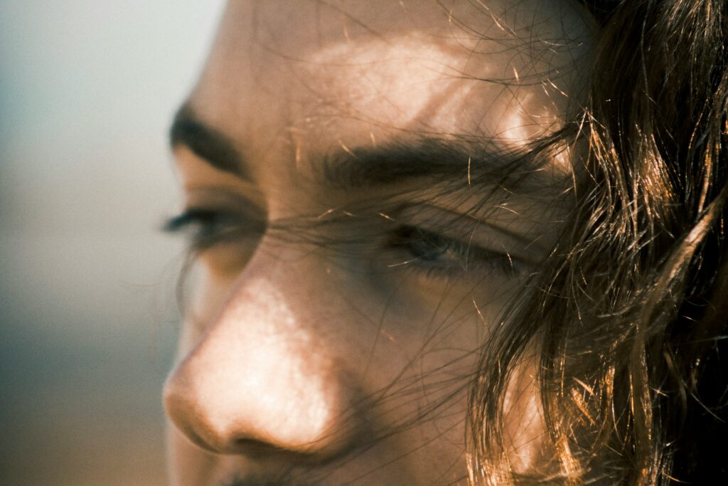 Women's upper face with dark hair flowing in the wind